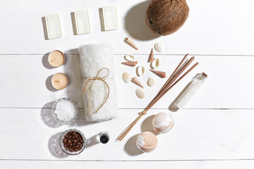 Fototapeta na wymiar Spa set with sea salt, essential oil, soap and towel decorated with seashells on white wooden background