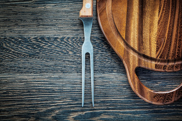 Meat fork carving board on wood background