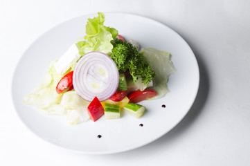 Vegetable salad with pesto and cheese on a white plate