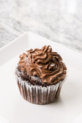 Chocolate cup cake with ganache chocolate cream on the white square plate