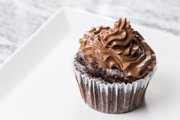 Chocolate cup cake with ganache chocolate cream on the white square plate