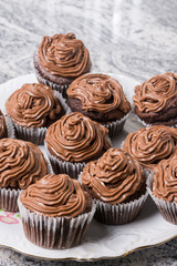 Plate full with chocolate cup cakes and with ganache chocolate cream