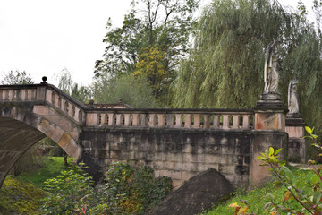Fototapeta premium Old stone footbridge over creek in the fall with autumn colors.