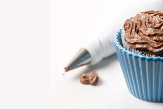 Chocolate Cup Cake With Ganache Chocolate Cream And Piping Bag In The Background On The White Marble Background