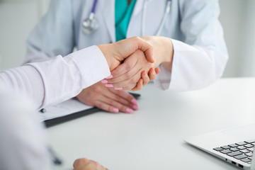Doctor and patient shaking hands, close-up.  Physician talking about medical examination results. Medicine, healthcare and trust concept