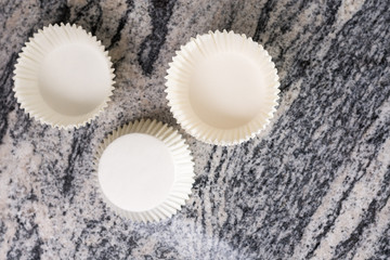 Flat lay above empty white cup cake cases containers on the grey granite marble background