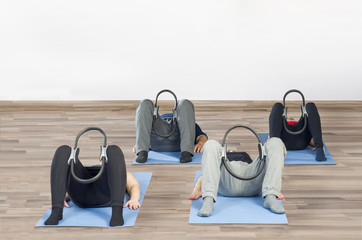 Diverse group of people a gym class sitting on Pilates ball doing ring Pilates exercise