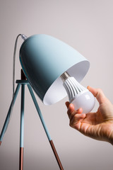 Changing the bulb for led bulb in table lamp in turquoise colours.