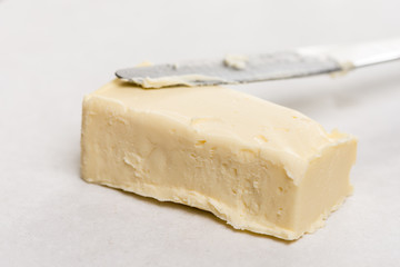 Slice of butter with kitchen knife on the white marble background table