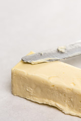Slice of butter with kitchen knife on the white marble background table