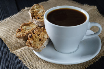 Coffee  cup on dark  wood background, with cantucci cookies