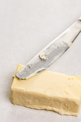 Slice of butter with kitchen knife on the white marble background table