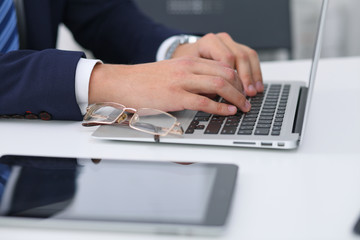 Fototapeta premium Businessman working by typing on laptop computer. Man's hands on notebook or business person at workplace. Employment or start-up concept