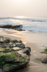 Beautiful sunrise with soft light and wet rocks at beach of Atlantic ocean, Ghana, West Africa