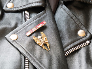 detail of black leather classic biker jacket with metal badges and zips
