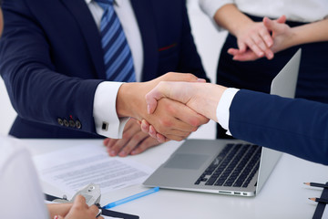 Business handshake at meeting or negotiation in the office, close-up. Partners are satisfied because signing contract or financial papers