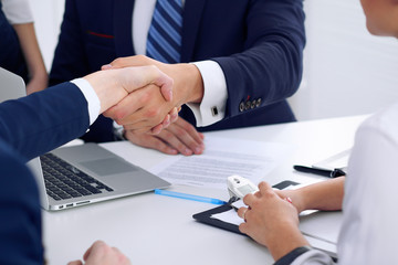 Business handshake at meeting or negotiation in the office, close-up. Partners are satisfied because signing contract or financial papers