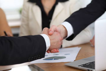 Close up of business people shaking hands at meeting or negotiation in the office. Partners are satisfied because signing contract