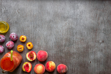 A glass of smoothies made of peach and plums on a wooden background