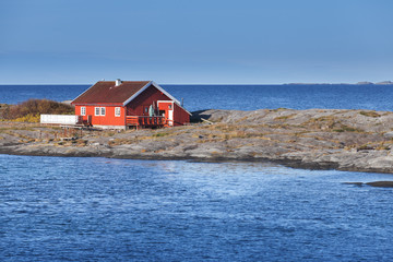Fototapeta na wymiar Red wooden house on rocky island. Norway