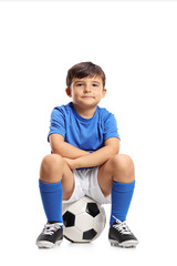 Boy in a blue jersey sitting on a football