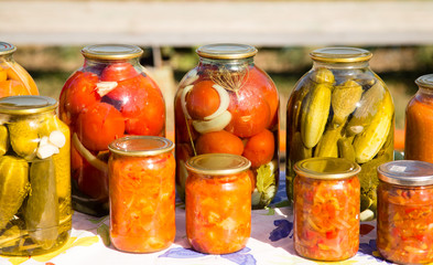 canned cucumbers and tomatoes in glass jars