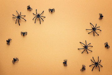 Halloween background with decorative spiders on orange backdrop. Copy space for text.