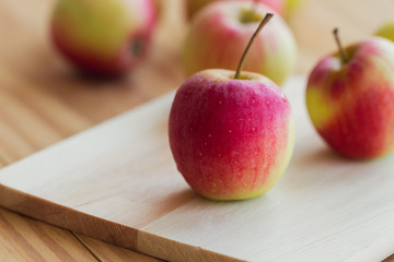 Stack of fuji apple and on cutting board put on wood table for background or wallpaper. Delicious sweet and juicy fuji apple for salad cooking or bakery.Fuji apple has origins in Japan.