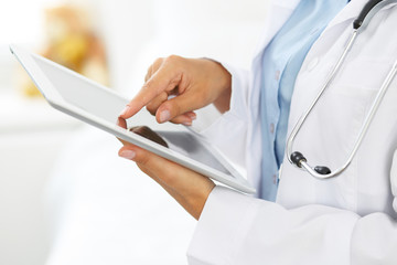 Woman doctor using tablet computer while standing straight in hospital