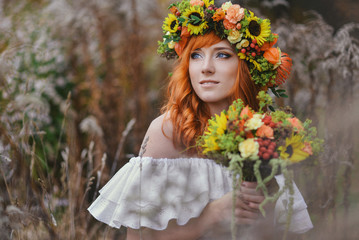 autumn portrait of romantic redhead woman with flowers in her hair in a wreath