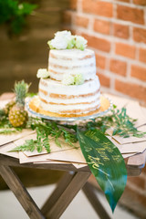 White wedding cake with leaves and decoration on the teble