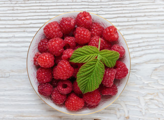Raspberries in a bowl on a wooden white table