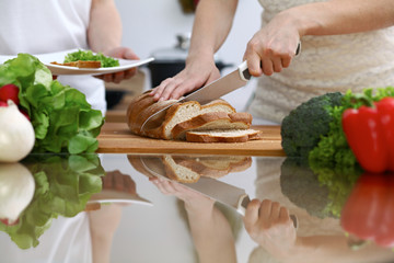 Close-up of human hands slicing bread in a kitchen. Friends having fun while cooking in the kitchen. Chef cook represent culinary masterclass
