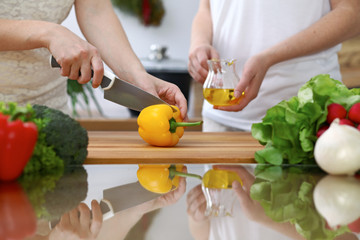 Close-up of  human hands  cooking in a kitchen. Friends having fun while preparing fresh salad. Vegetarian, healthy meal and friendship concept