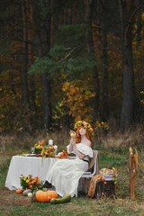 Autumn romantic redhead woman sits near floristic decor table. rustic