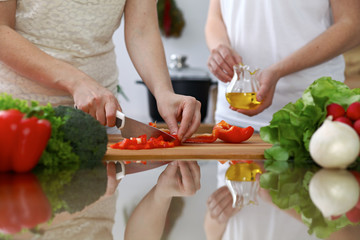 Close-up of  human hands  cooking in a kitchen. Friends having fun while preparing fresh salad. Vegetarian, healthy meal and friendship concept