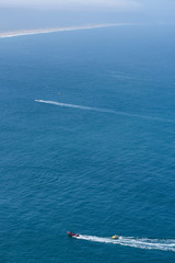 Fototapeta premium Tourists taking ride by speed boat on rubber tube boat on waves in ocean, birds eye view