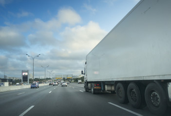 Obraz na płótnie Canvas White truck on asphalt road under blue sky with clouds