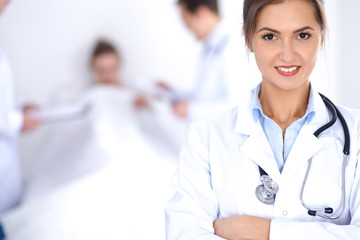 Fototapeta premium Female doctor smiling on the background with patient in the bed