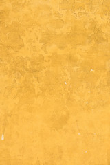 Old concrette wall covered in yellow painted weathered stucco texture background