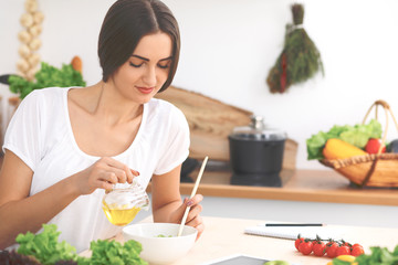 Beautiful  Hispanic or latin american woman is holding wooden spoon while cooking salad  in the kitchen.