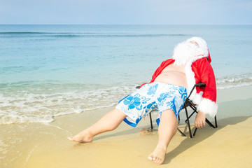 Funny Santa in shorts on the beach.