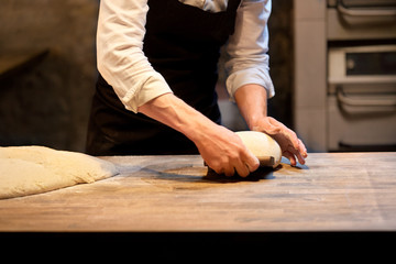 baker portioning dough with bench cutter at bakery