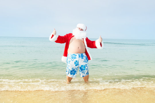 Funny Santa in shorts on the beach.