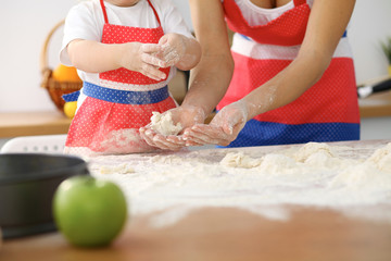 Mother and her cute daughter hands prepares the dough on wooden table. Homemade pastry for bread or pizza. Bakery background