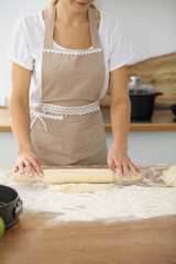 Female hands making dough for pizza or bread while using rolling pin. Baking concept
