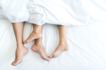 Closeup Feet of couple man and woman making love or sex on bed under blanket at hotel, home, sweet valentine concept.