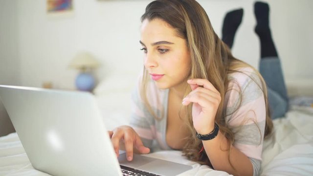 A beautiful woman studiying in the bedroom with laptop