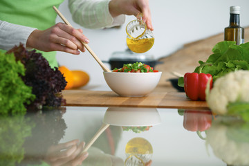 Closeup of human hands cooking vegetables salad in kitchen on the glass  table with reflection
