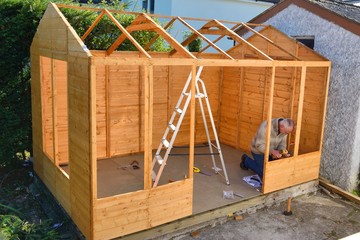 Man at work, completing building of a cabin, shed, summer house.